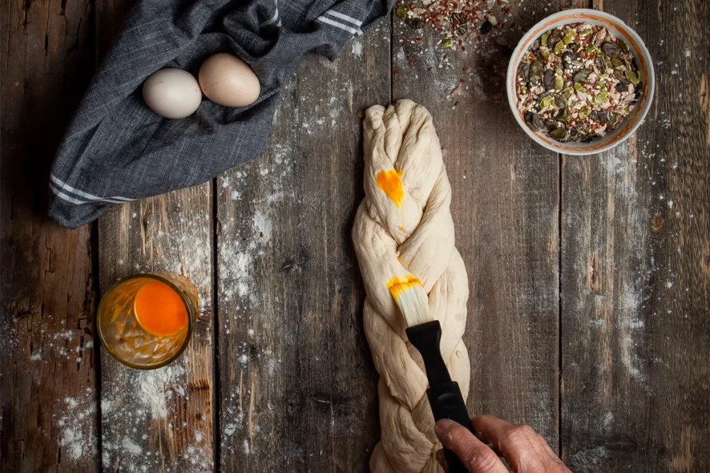 آموزش مرحله‌به‌مرحله آماده‌سازی نان بابکا؛ از ورز دادن و بافت خمیر تا رومال با زرده تخم‌مرغ برای بافتی نرم، طعمی غنی و ظاهری حرفه‌ای.